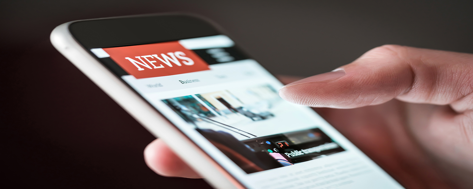 Banner of hand holding a smartphone. The smartphone screen displays a NEWS app website.